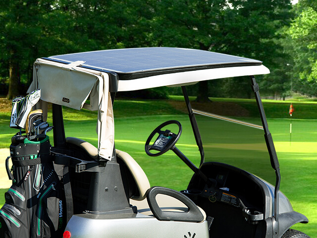 A silhouette of a man playing golf next to his golf buggy