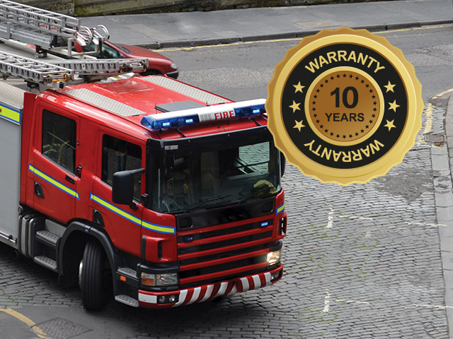 A fire engine turnng at a cobbled road junction with 10 years warranty badge in corner of photograph